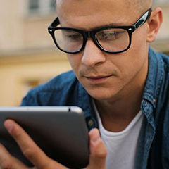 person wearing glasses looking at tablet
