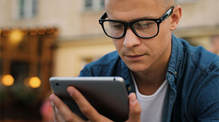 person wearing glasses looking at tablet