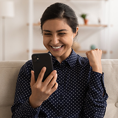 A person smiling at their phone making a "yes" gesture with their free hand