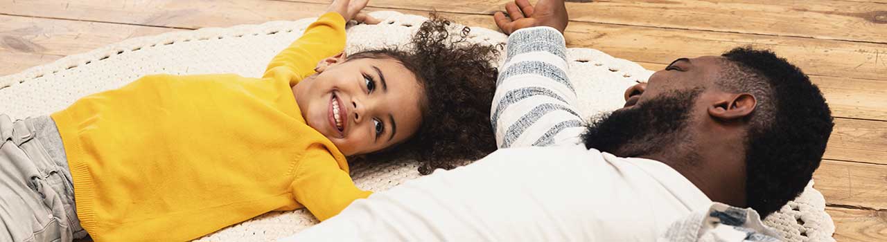 child and parent laying on the floor smiling at each other