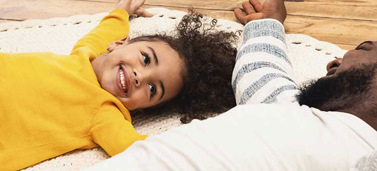 child and parent laying on the floor smiling at each other