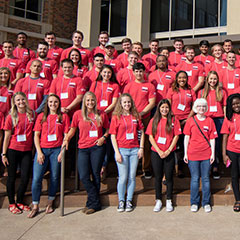 Several dozen D.R.Horton interns standing together in red shirts for a group photo on front of D.R.Horton office.