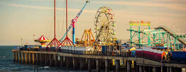 The carnival rides and ferris wheel of the Coney Island boardwalk.