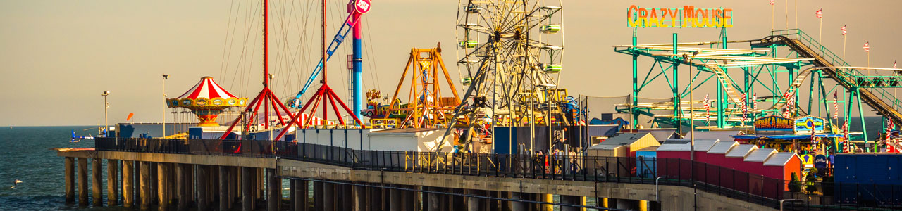 The carnival rides and ferris wheel of the Coney Island boardwalk.