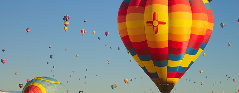 Dozens of hot air ballons rising to the sky from the desert floor.